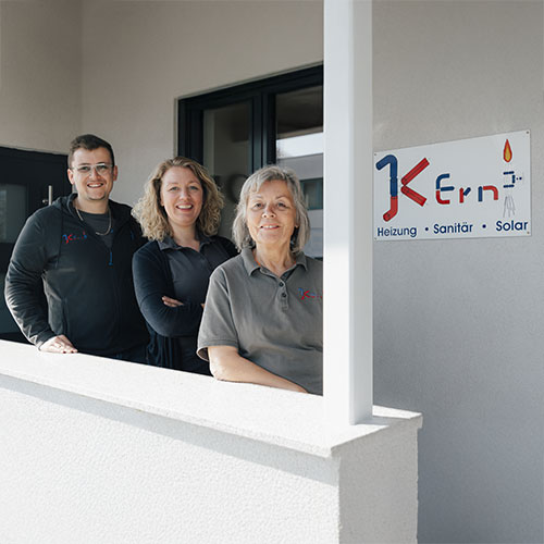 Drei lächelnde Personen vor einem Firmengebäude mit "Kern"-Schild.